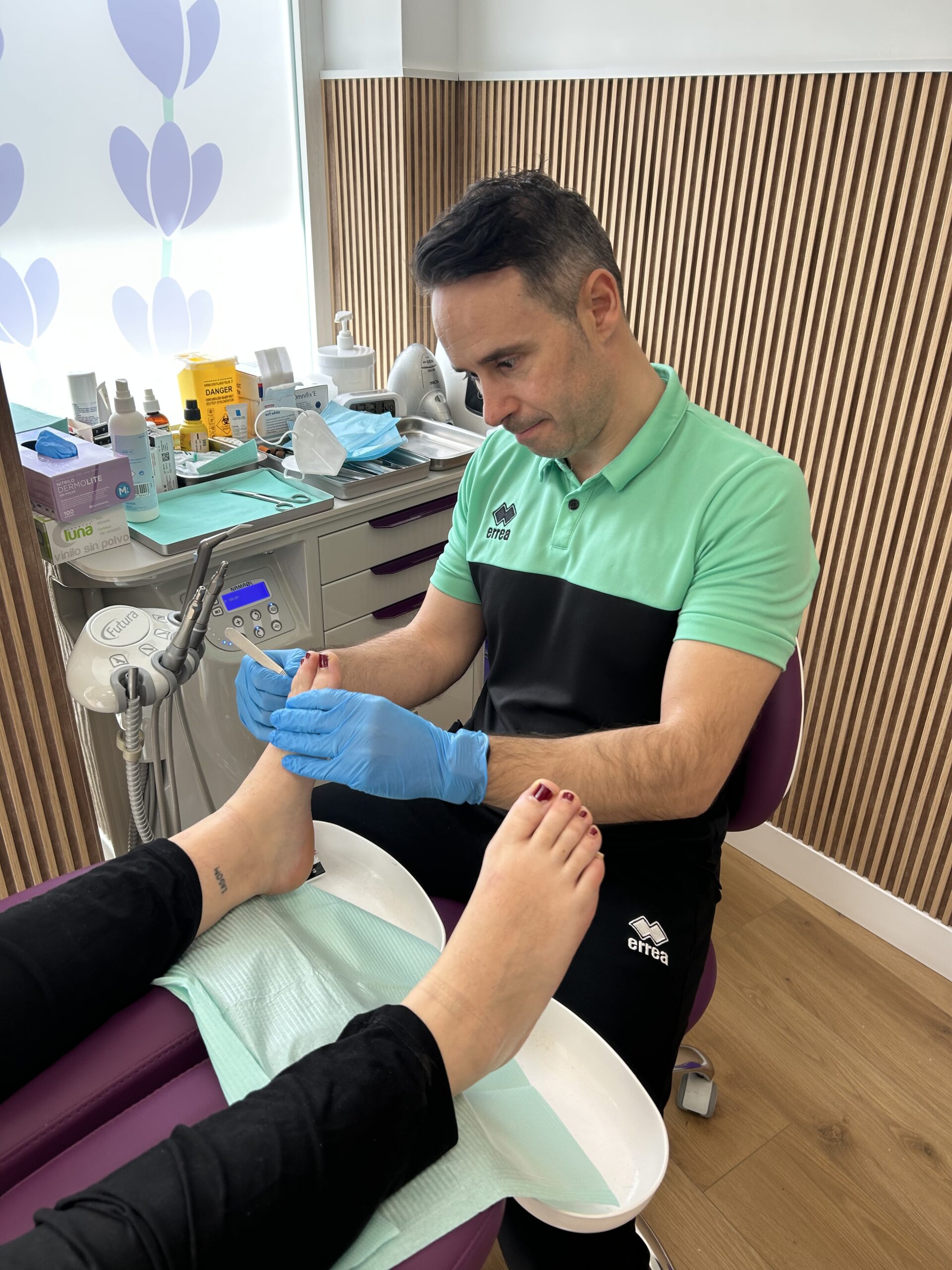 Podólogo realizando un tratamiento de cuidado y revisión de pies a una paciente, utilizando guantes y herramientas especializadas