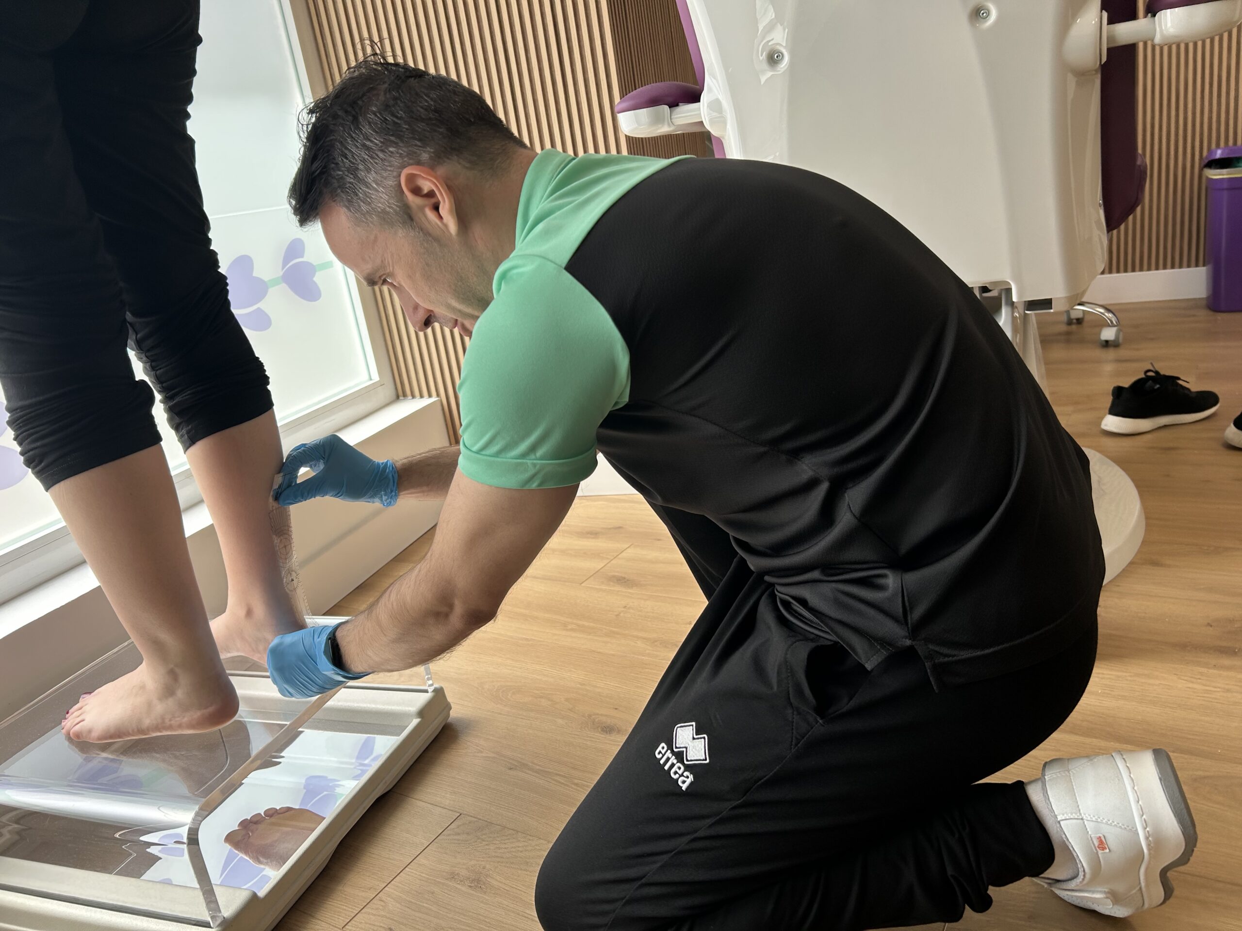 Profesional sanitario explicando un análisis de huella plantar en una pantalla dentro de la clínica.