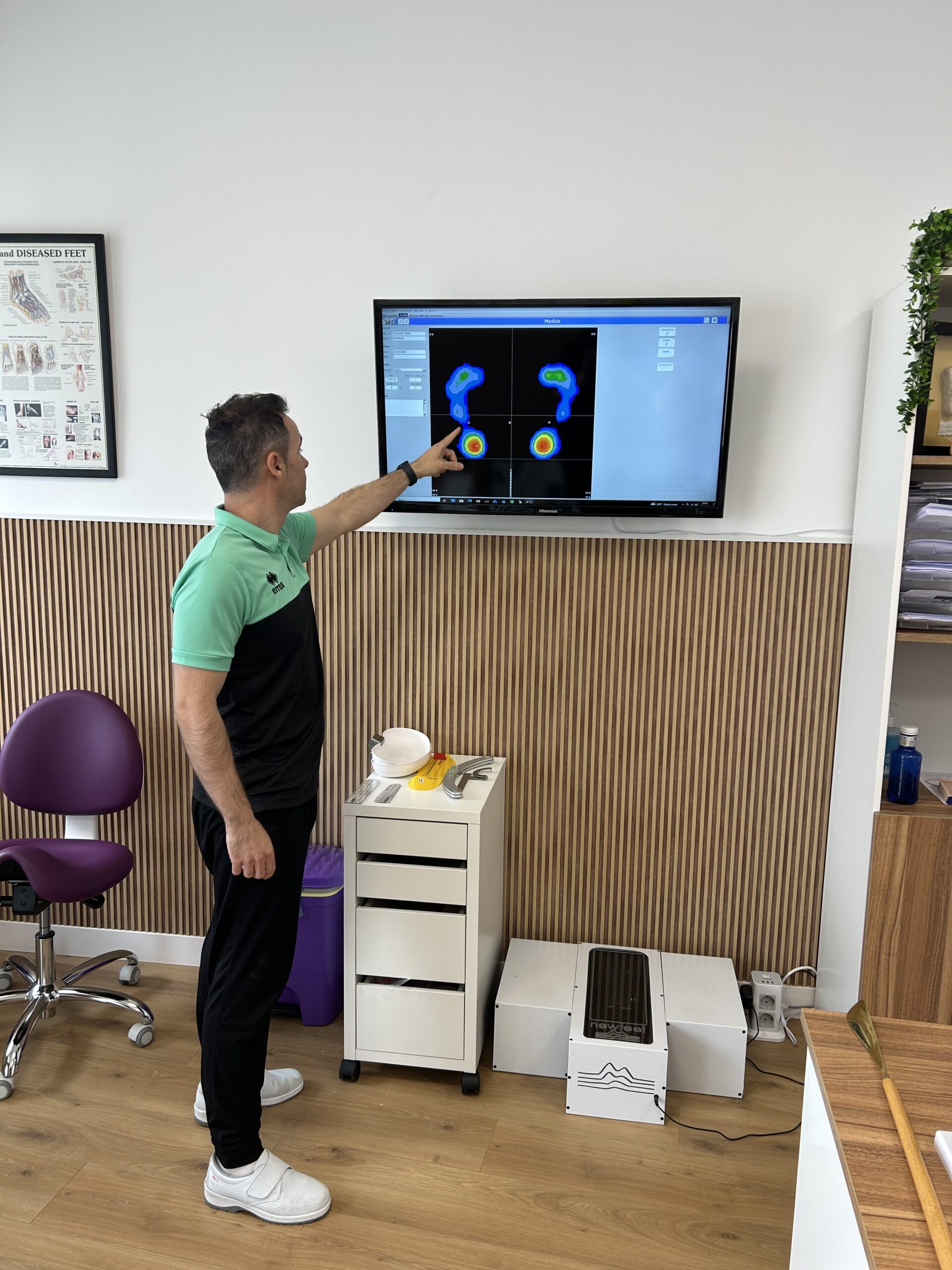Especialista señalando en una pantalla el análisis de la presión plantar, mostrando un estudio detallado de la pisada.