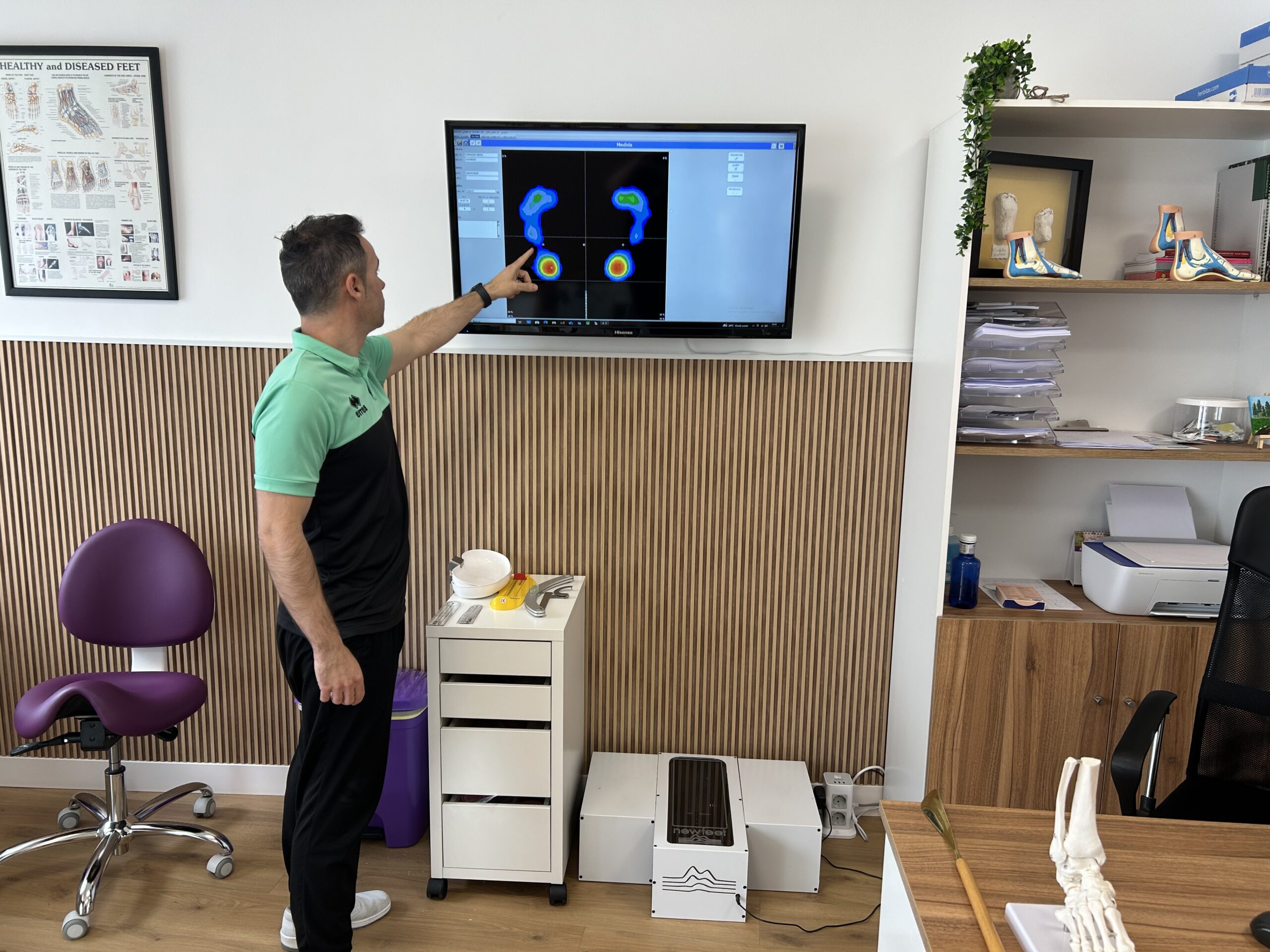Especialista señalando en una pantalla el análisis de la presión plantar, mostrando un estudio detallado de la pisada